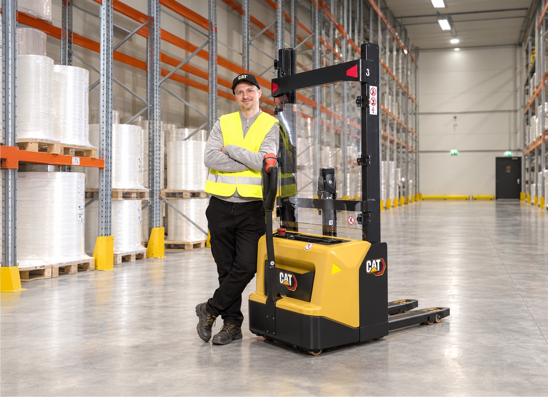 Servisní technik BPS v reflexní vestě opřený o vysokozdvižný vozík Cat ve skladu